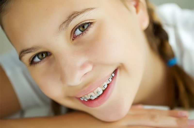 Orthodontist with blue gloves examining patient's smile
