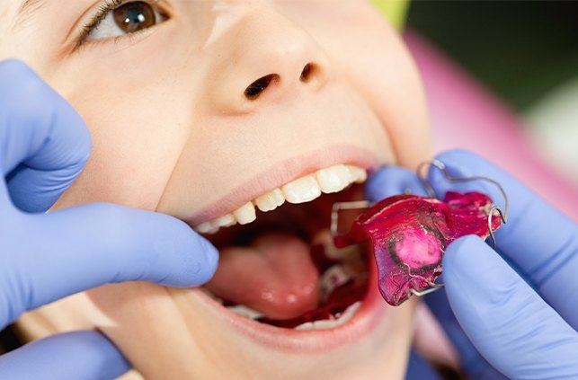 Orthodontist examining child's smile during pediatric orthodontics visit