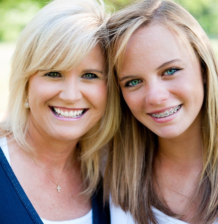 Young woman with traditional braces and her mother smiling outdoors