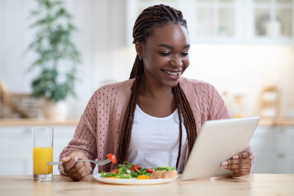 Woman with braces smiling while eating lunch and reviewing paperwork