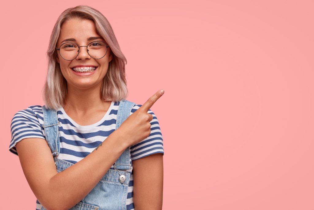 Woman with glasses and braces pointing