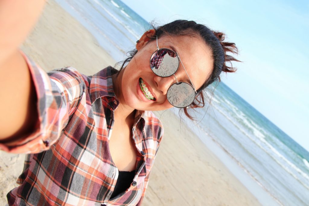 Woman with braces taking selfie on beach