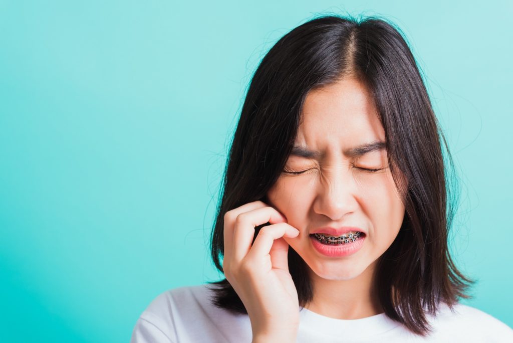 Woman with braces holding cheek due to irritation